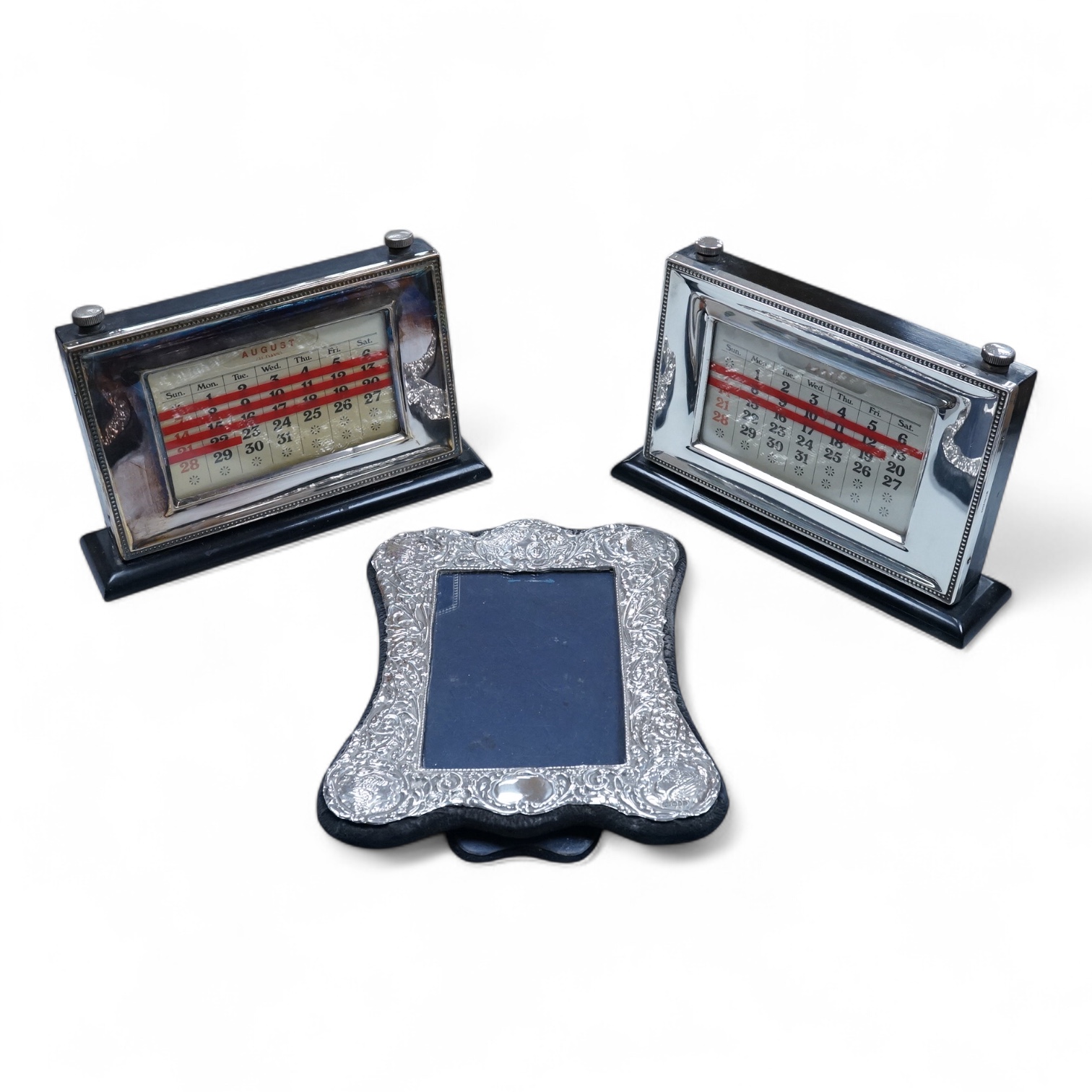 Two modern silver mounted ebonised desk calendars, including one retailed by Asprey, width 21.3cm and a modern silver mounted photograph frame.